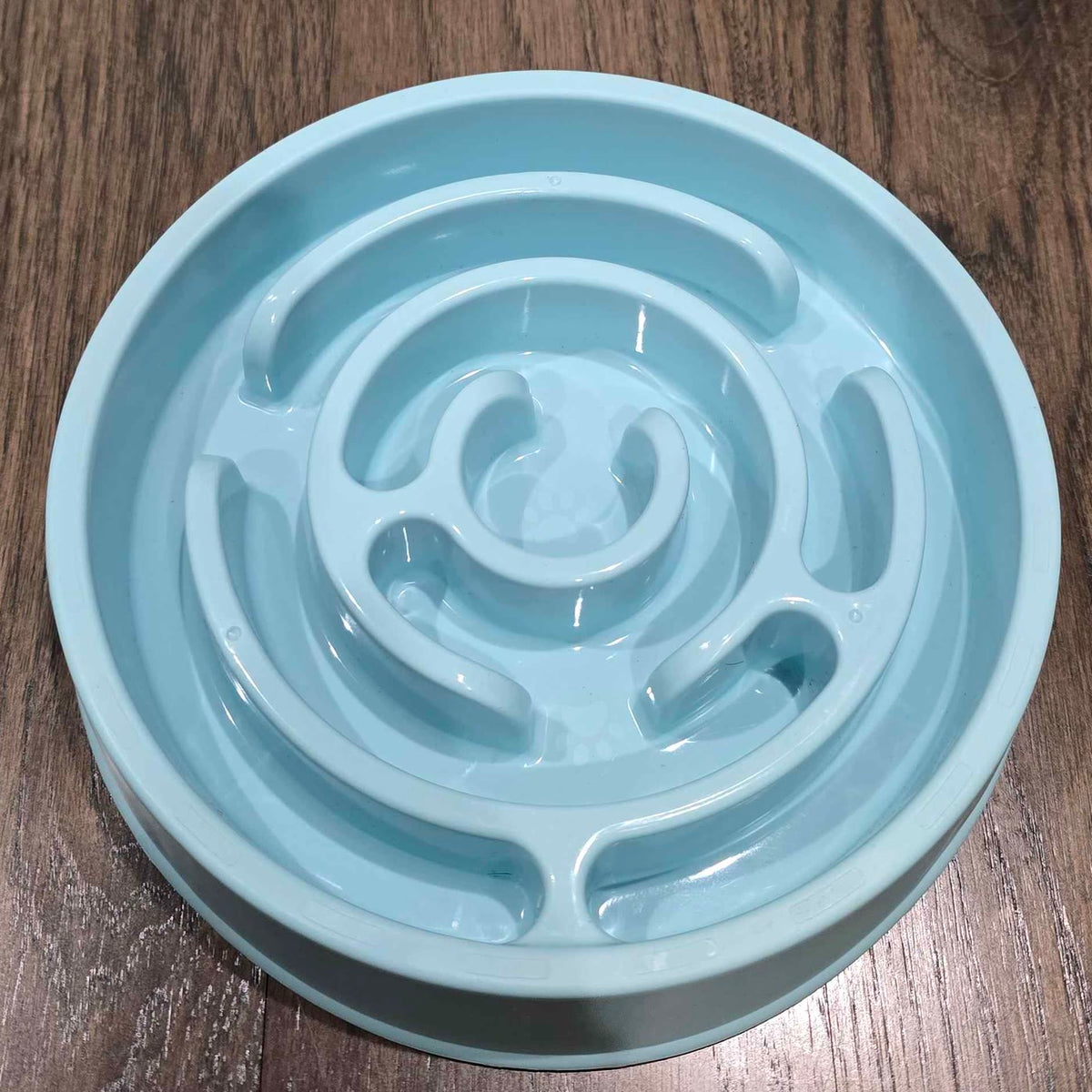 A light blue slow feeder bowl moulded into a spiral maze that a dog has to work its food out of.