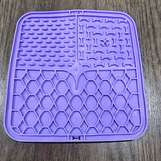 A purple lick mat with three textured zones that slow a dog down as it licks food off the surface.