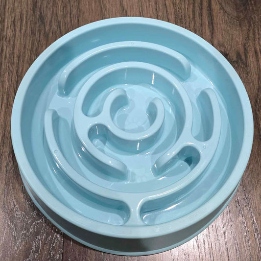 A light blue slow feeder bowl moulded into a spiral maze that a dog has to work its food out of.